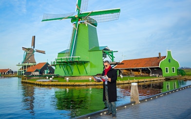 Man with a map near windmills in Zaanse Schans, Netherlands.