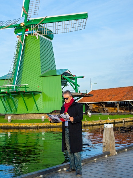 Man with a map near windmills in Zaanse Schans, Netherlands.