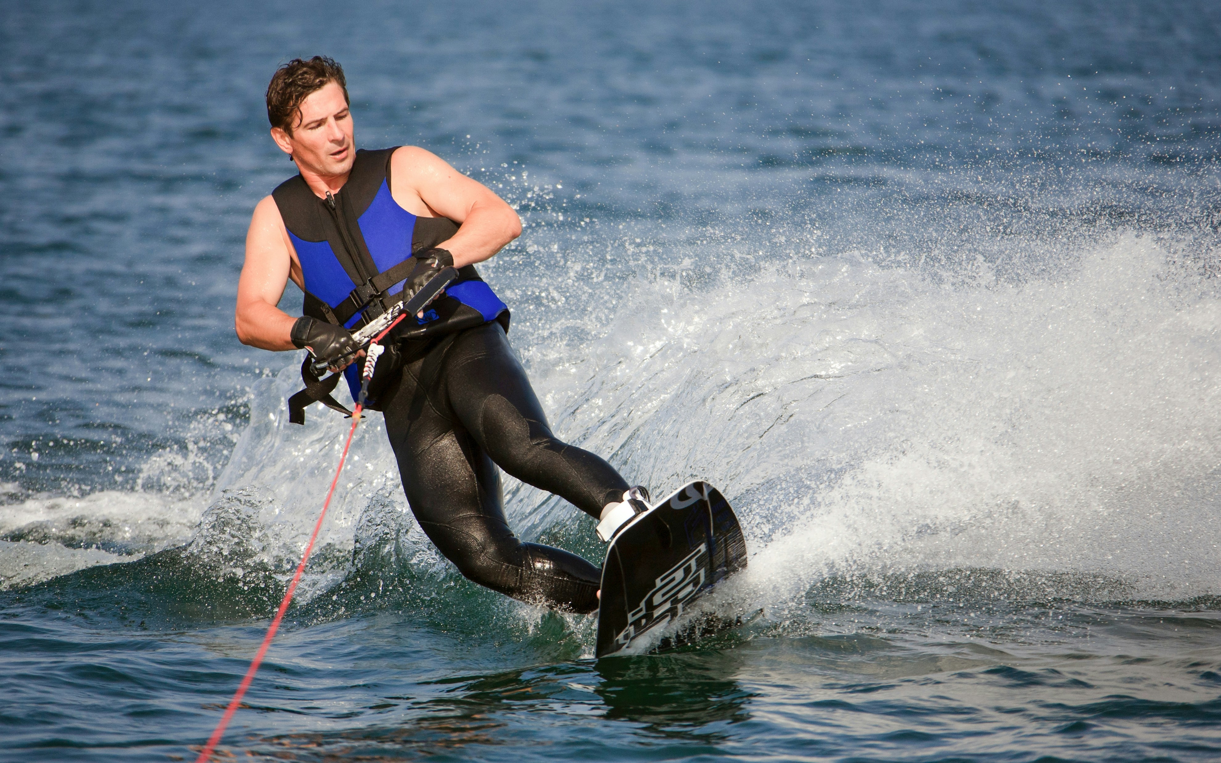 Wakeboarder sliding on water with splash.