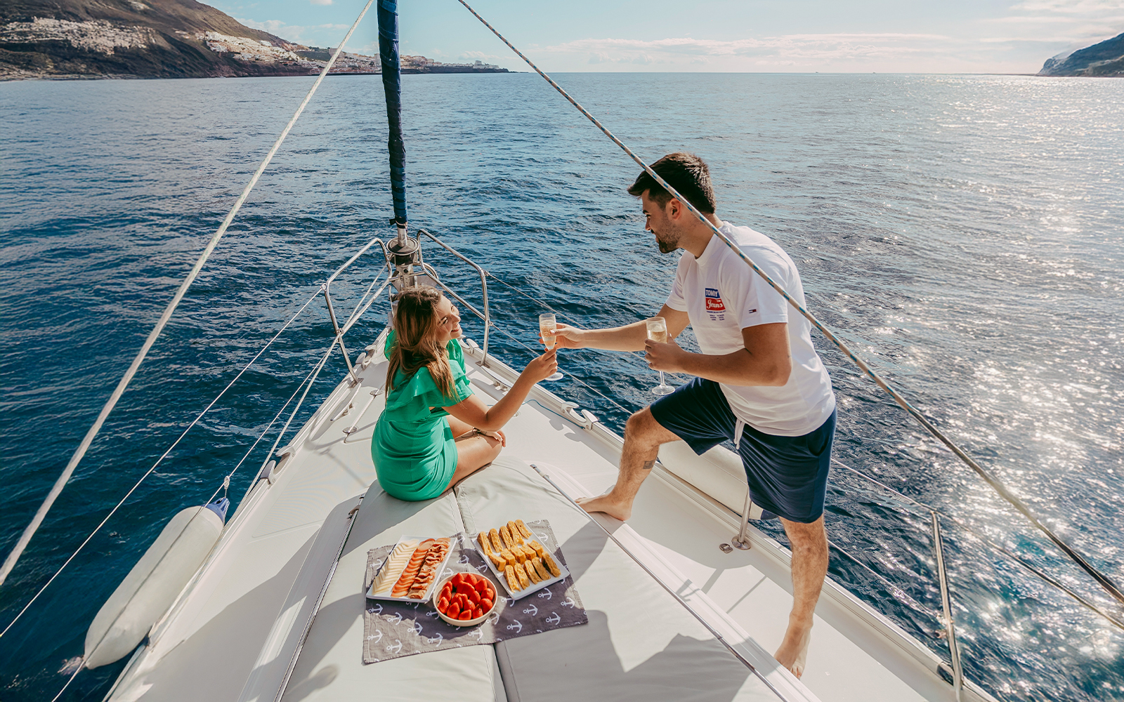 Tourists enjoying drinks on a private sailboat with snacks, ocean view, Tenerife coast.