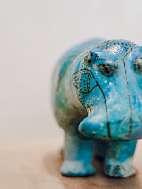 Bright blue faience hippopotamus figurine with black details at Metropolitan Museum of Art.