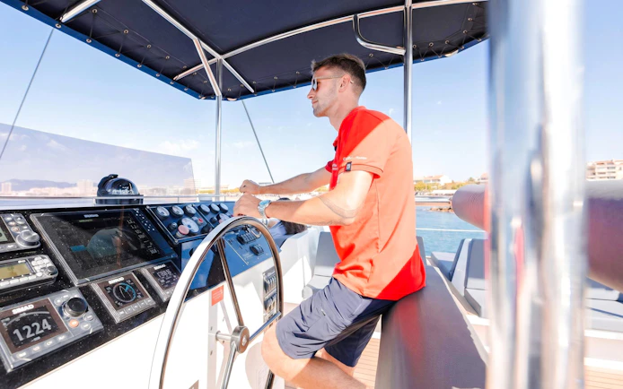 Catamaran captain steering in Villefranche bay during snorkeling cruise.