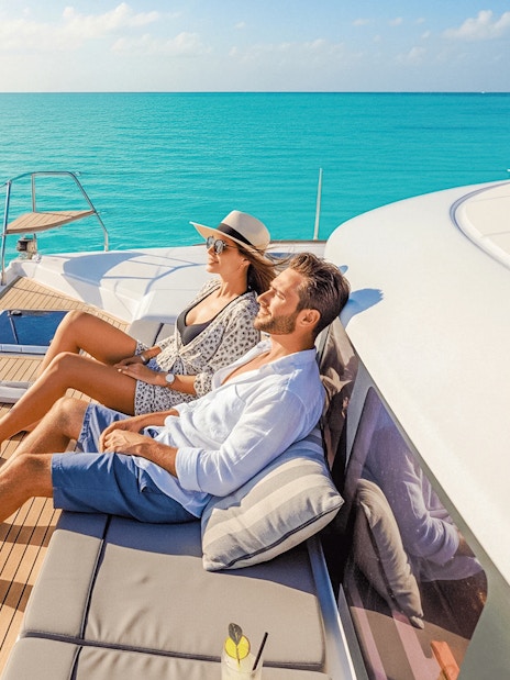 Tourists relaxing with drinks on a catamaran, Isla Mujeres tour.