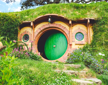 Hobbiton movie set tour featuring Bag End with green door and garden.