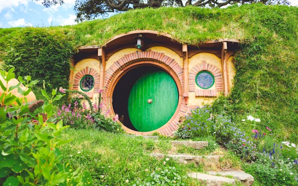 Hobbiton movie set tour featuring Bag End with green door and garden.