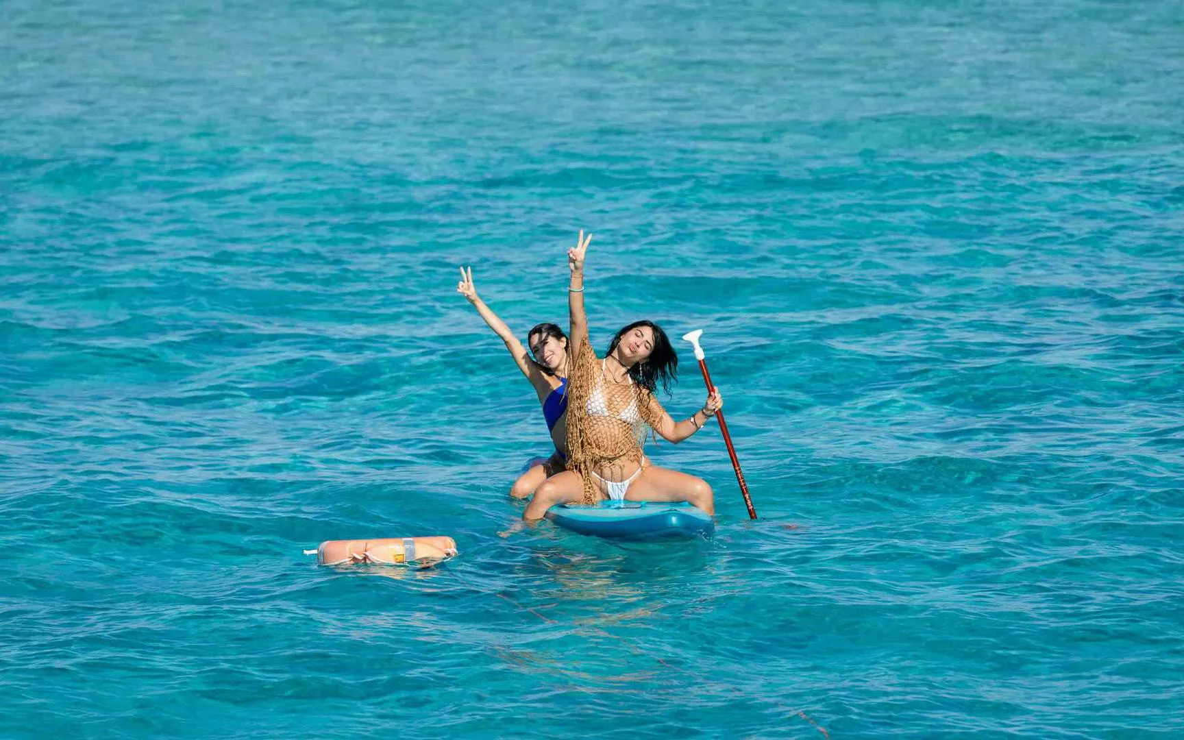 Tourists paddleboarding on clear waters during Ibiza to Formentera cruise.