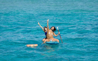 Tourists paddleboarding on clear waters during Ibiza to Formentera cruise.