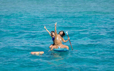 Tourists paddleboarding on clear waters during Ibiza to Formentera cruise.