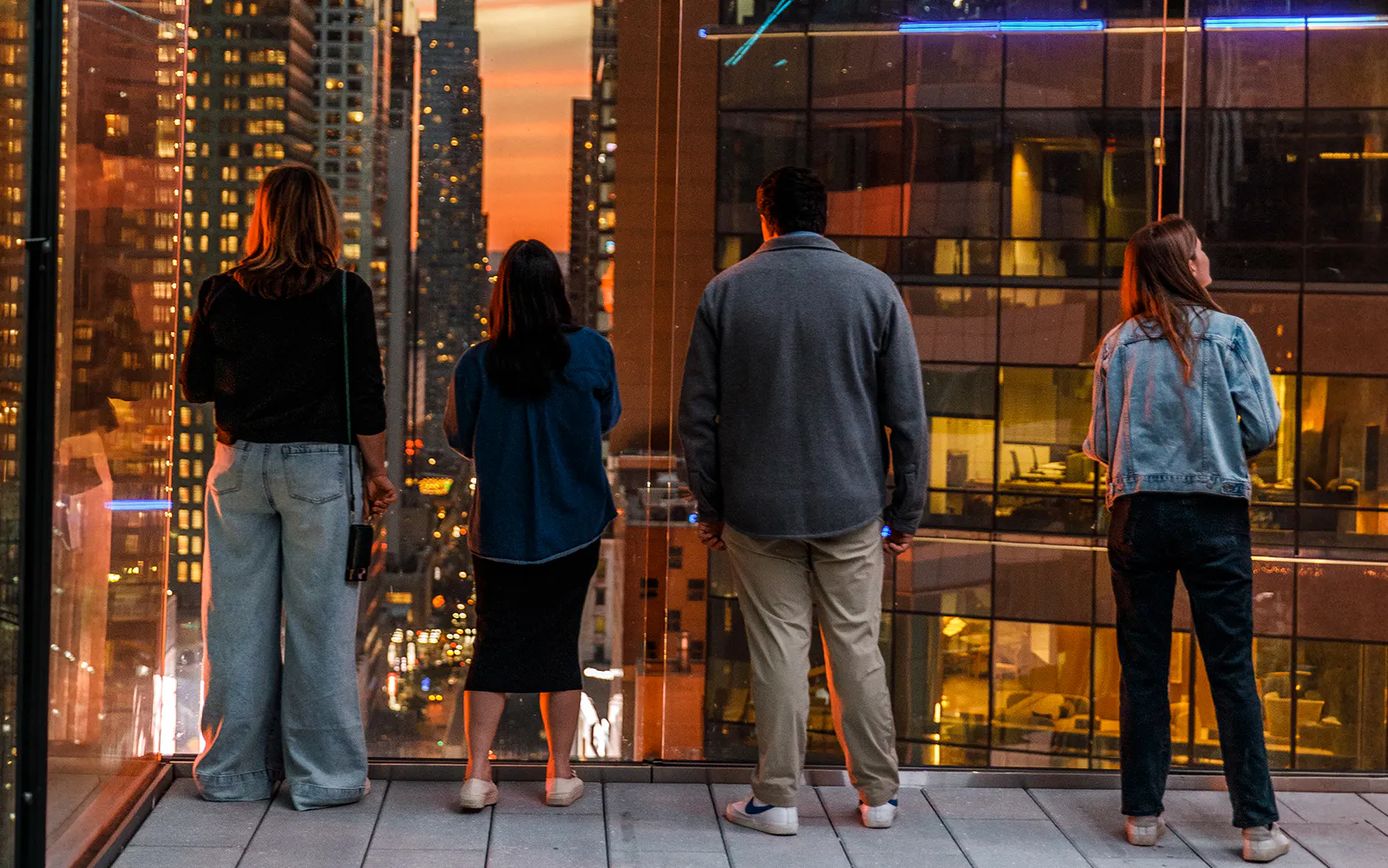 Visitors enjoying sunset views from One Times Square Skywalk in New York City.
