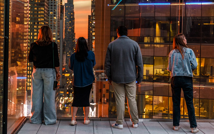 Visitors enjoying sunset views from One Times Square Skywalk in New York City.