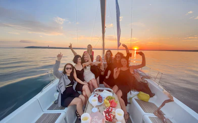 Guests enjoying a sunset cruise from Sopot Pier with drinks and snacks on a sailboat.