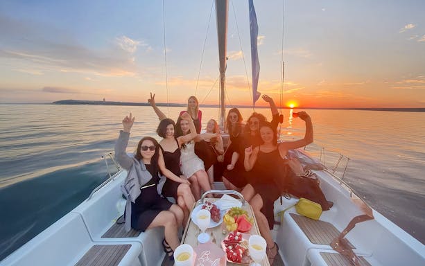 Guests enjoying a sunset cruise from Sopot Pier with drinks and snacks on a sailboat.