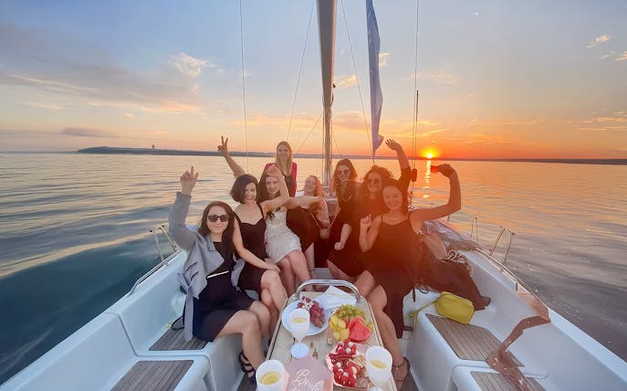 Guests enjoying a sunset cruise from Sopot Pier with drinks and snacks on a sailboat.