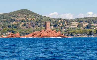 Catamaran cruise view of red rock island and tower in Villefranche bay.