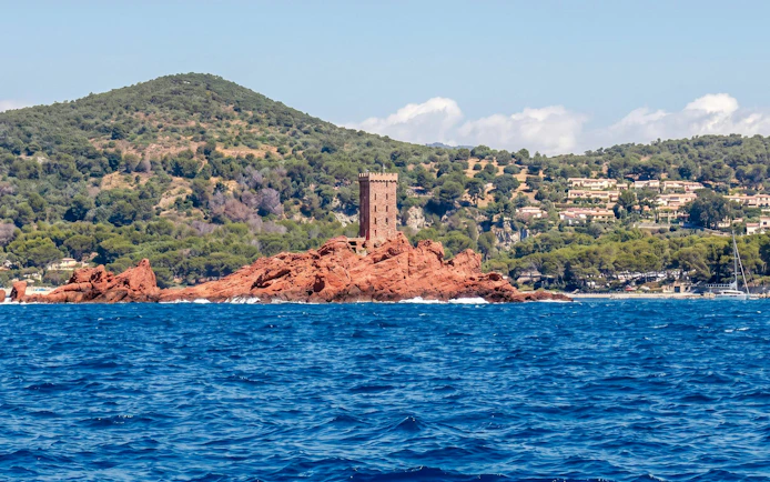 Catamaran cruise view of red rock island and tower in Villefranche bay.