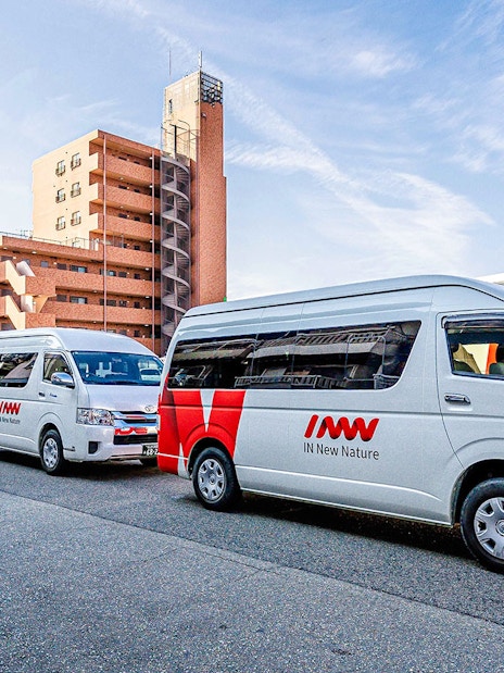 Kansai Airport shared shuttle vans parked in a row near buildings.