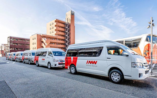 Kansai Airport shared shuttle vans parked in a row near buildings.