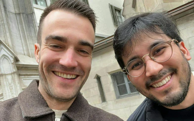 Two people smiling in front of a historic building in Zurich during a self-guided city exploration game.