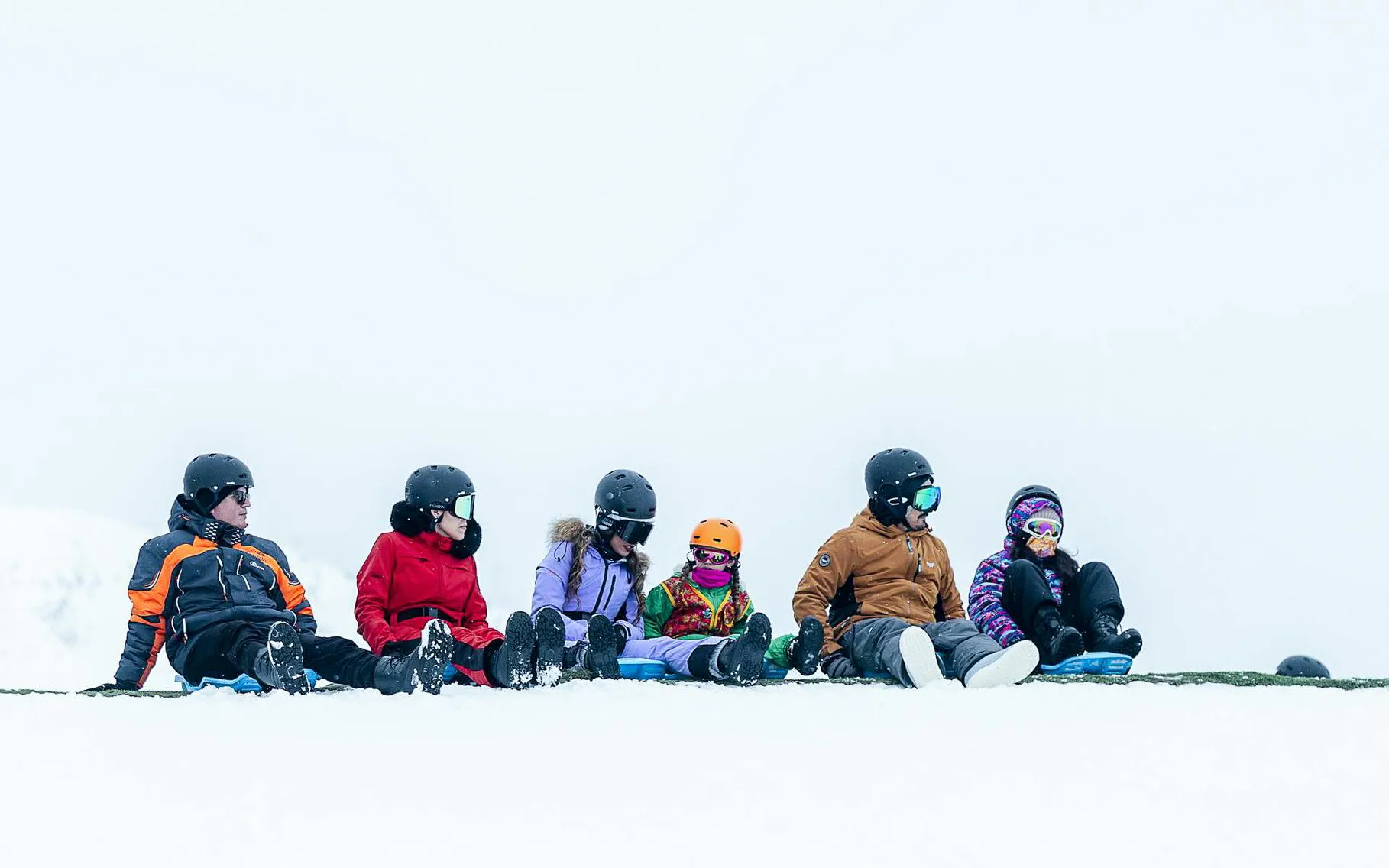 Tourists sitting on snow at Valle Nevado ski resort, Andes Mountains, Chile.