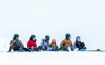 Tourists sitting on snow at Valle Nevado ski resort, Andes Mountains, Chile.