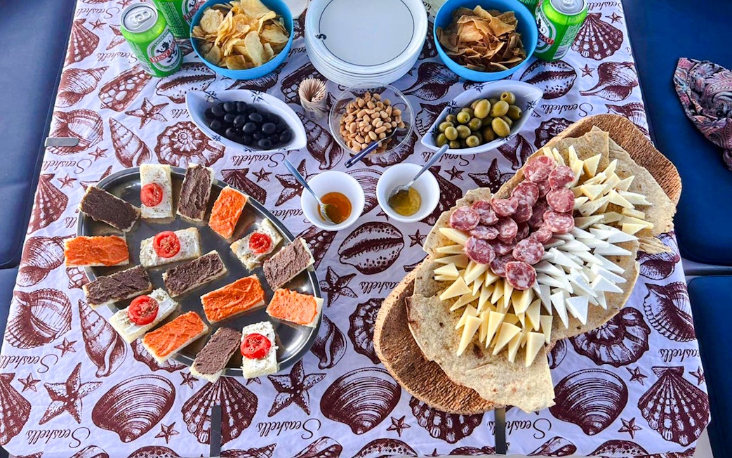 Assorted snacks and drinks on a table during a catamaran tour in La Maddalena.