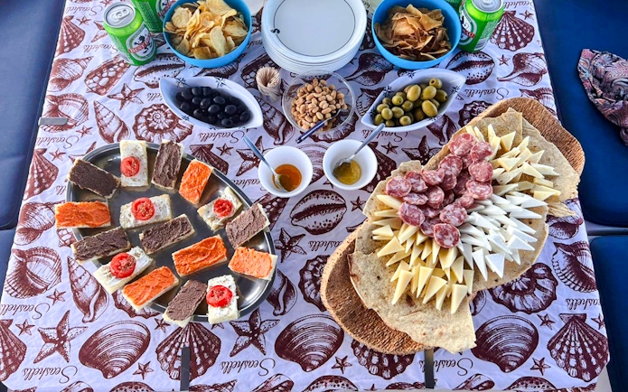 Assorted snacks and drinks on a table during a catamaran tour in La Maddalena.