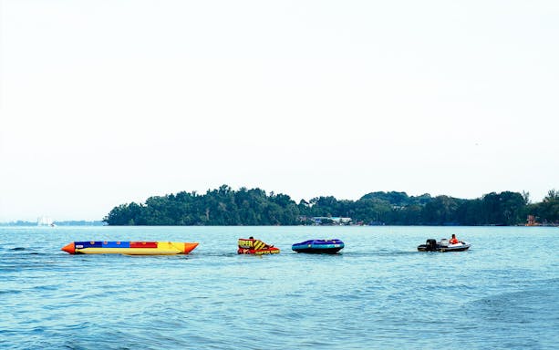 Banana boat and speedboat on water near Paradise 101 island.