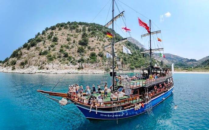 Pirate ship tour with passengers near Saranda coastline.