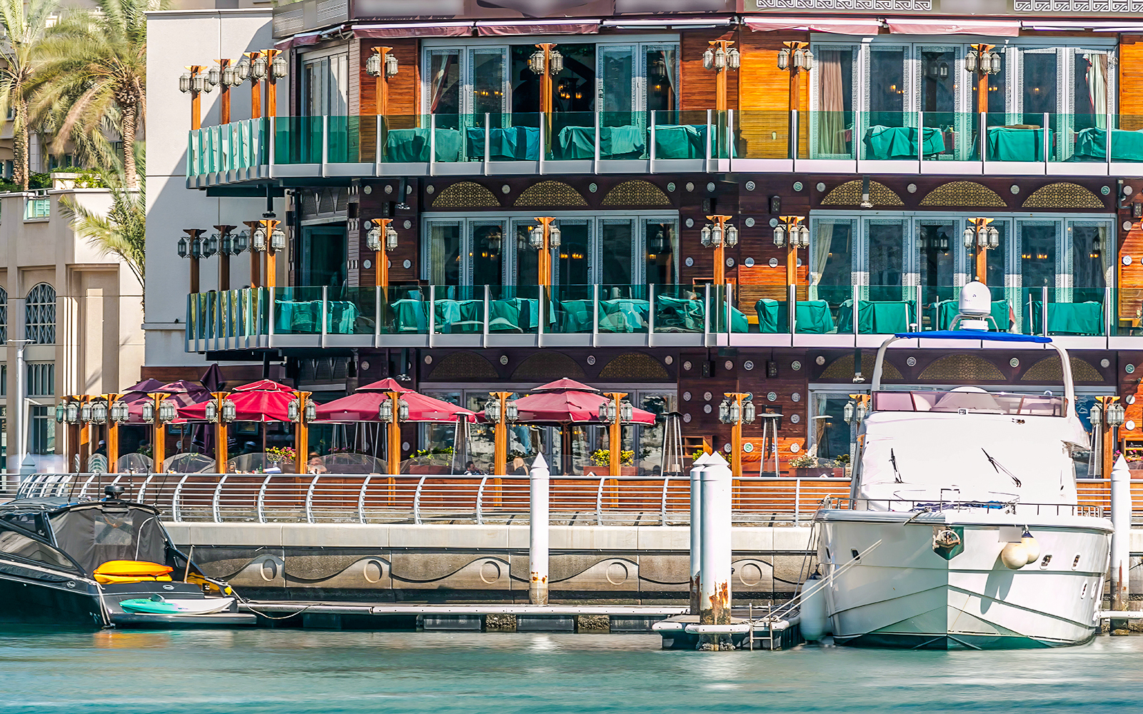 Promenade restaurant in Dubai with outdoor seating and docked yacht.