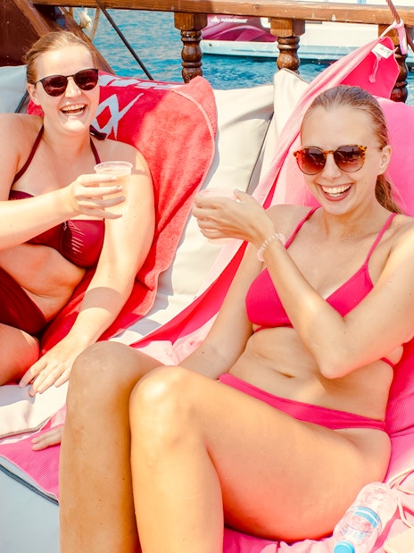 People relaxing on a daytime cruise from Rhodes, enjoying drinks on deck.