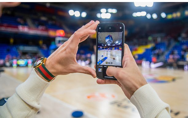 Capturing FC Barcelona Palau court on phone during immersive tour experience.
