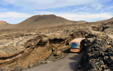 Bus navigating volcanic landscape in Timanfaya National Park, Lanzarote.