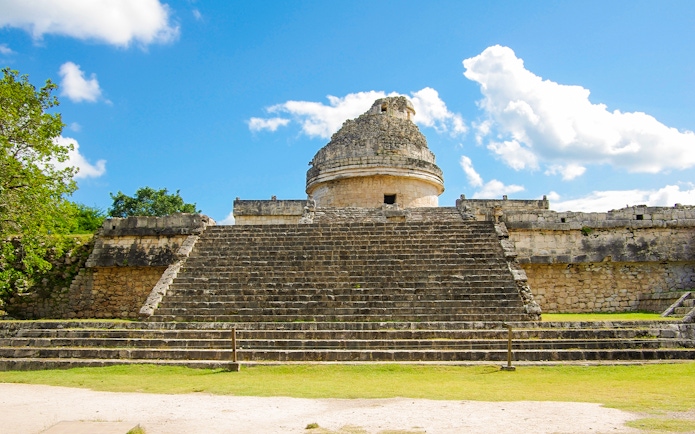 Chichen Itza observatory with stone steps under a blue sky.
