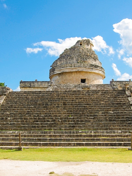Chichen Itza observatory with stone steps under a blue sky.