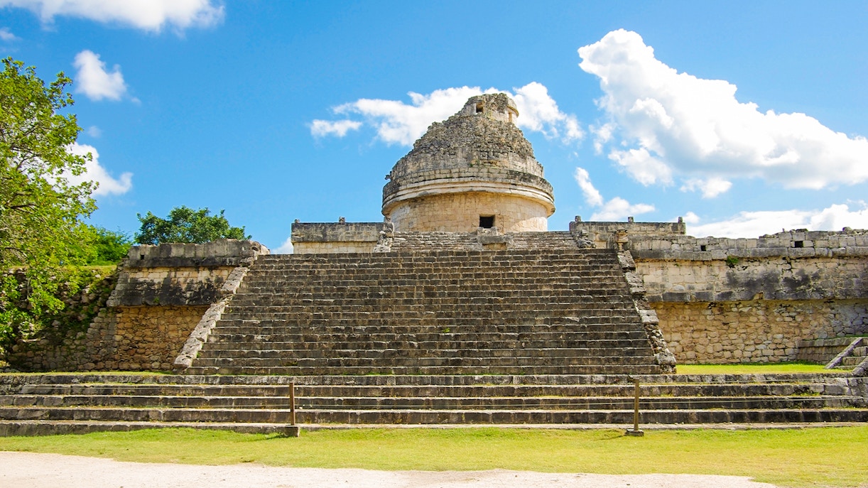 Chichen Itza observatory with stone steps under a blue sky.