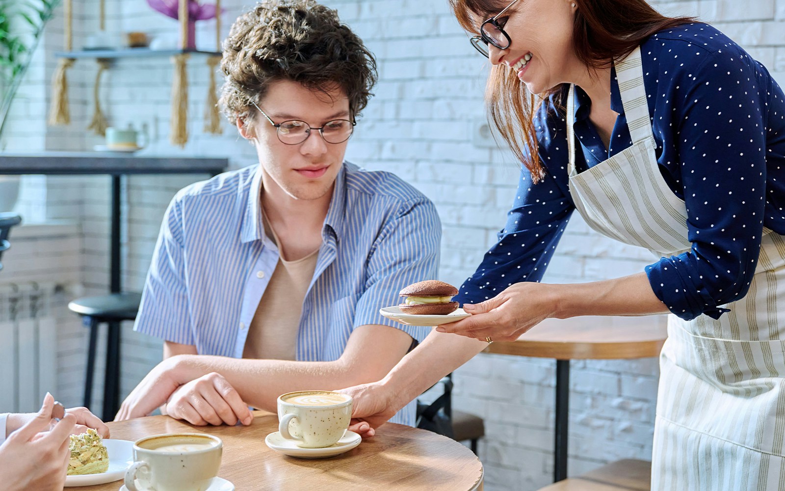 Server offering dessert to a customer in a cozy cafeteria.