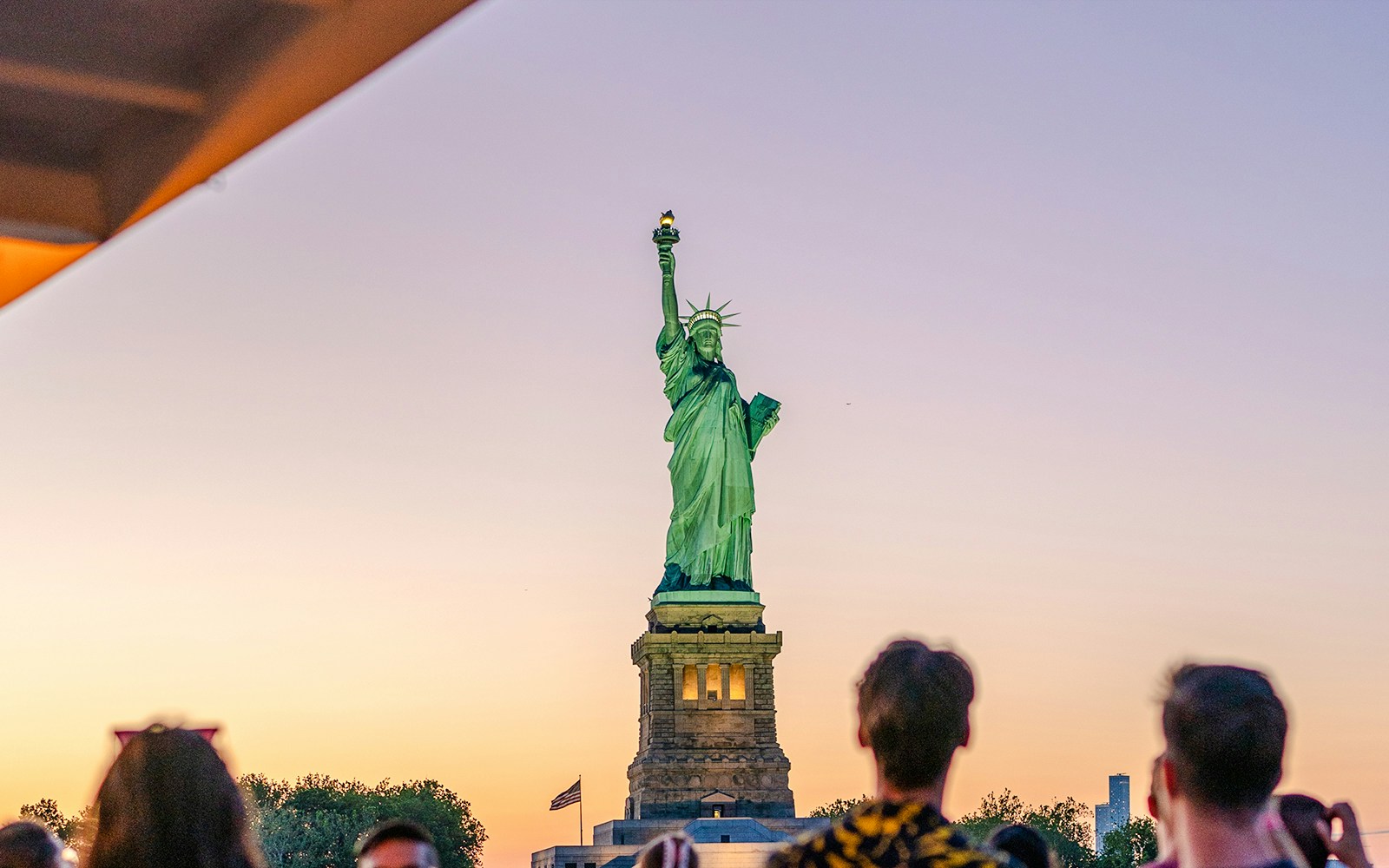 Statue of Liberty at sunset with Circle Line sightseeing cruise boat in New York City.
