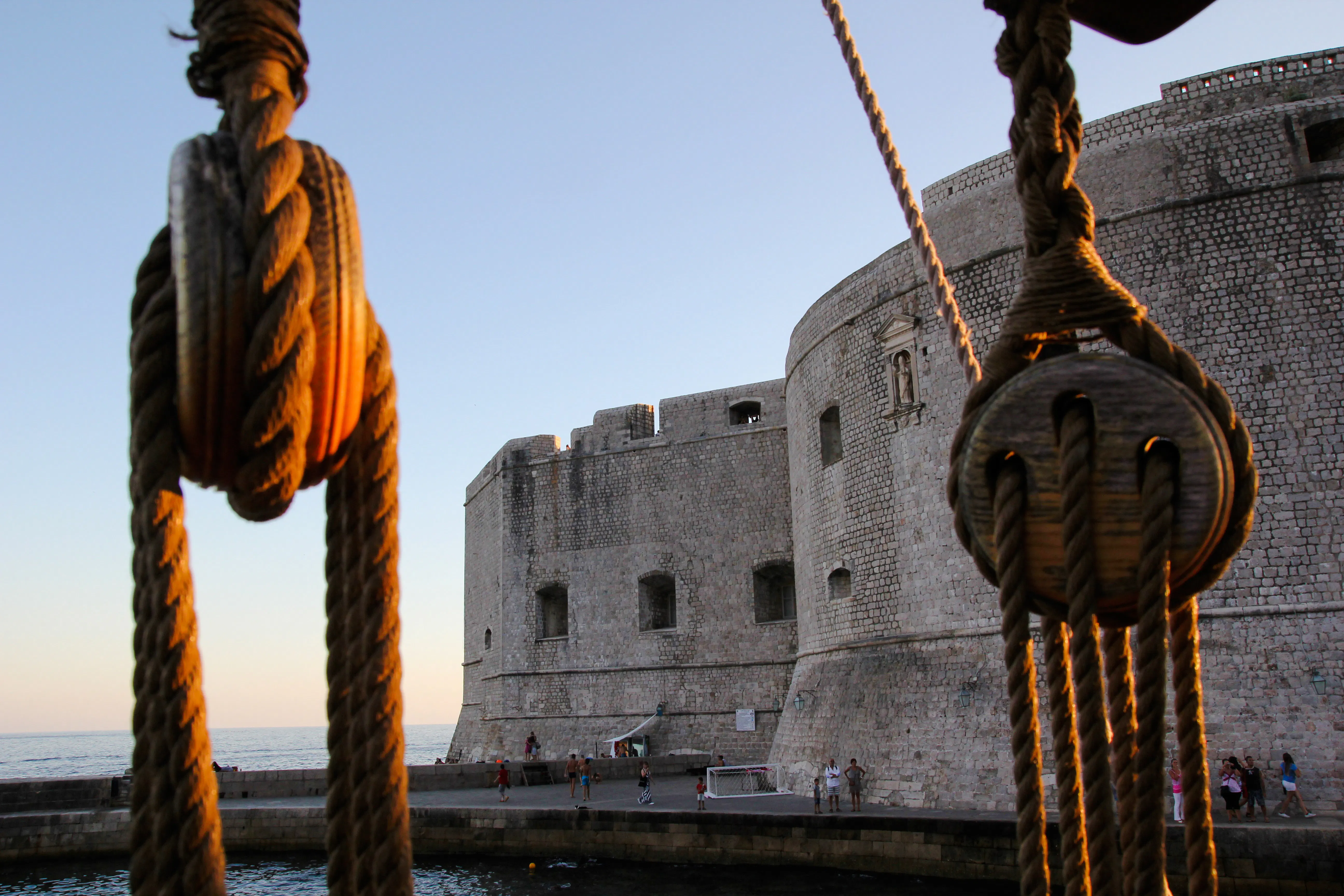 Ropes of a pirate ship with Dubrovnik's Old Town walls in the background.