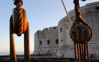 Ropes of a pirate ship with Dubrovnik's Old Town walls in the background.