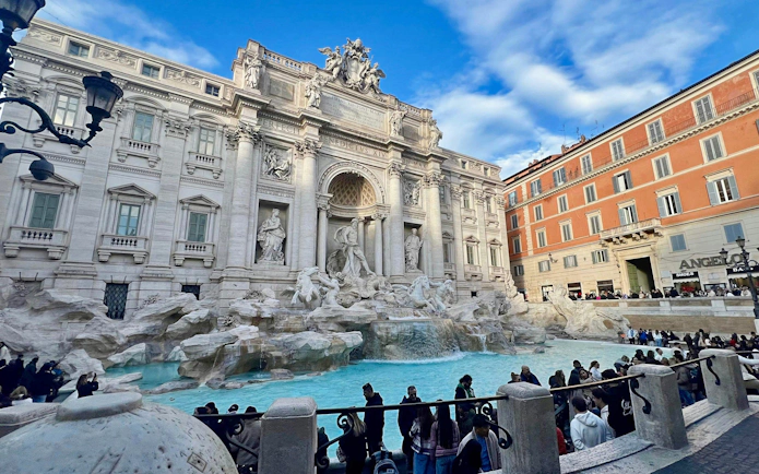 Trevi Fountain in Rome with tourists gathered around the iconic Baroque architecture.