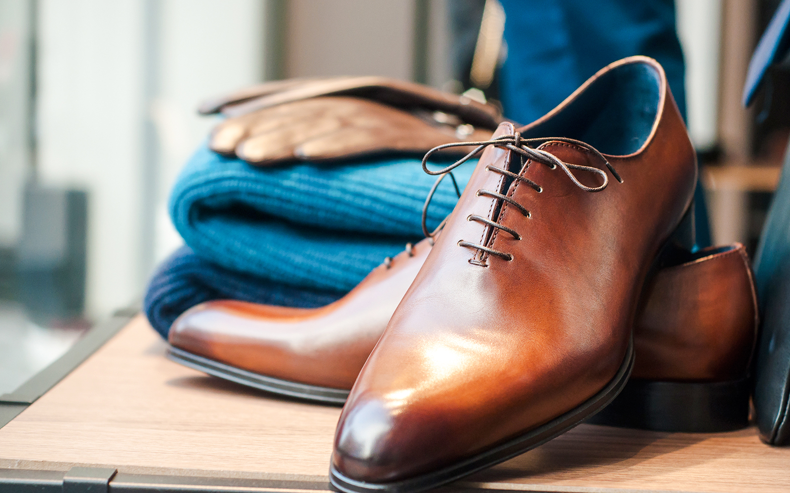 Brown leather dress shoes and folded blue sweater, suitable for Moulin Rouge dress code.