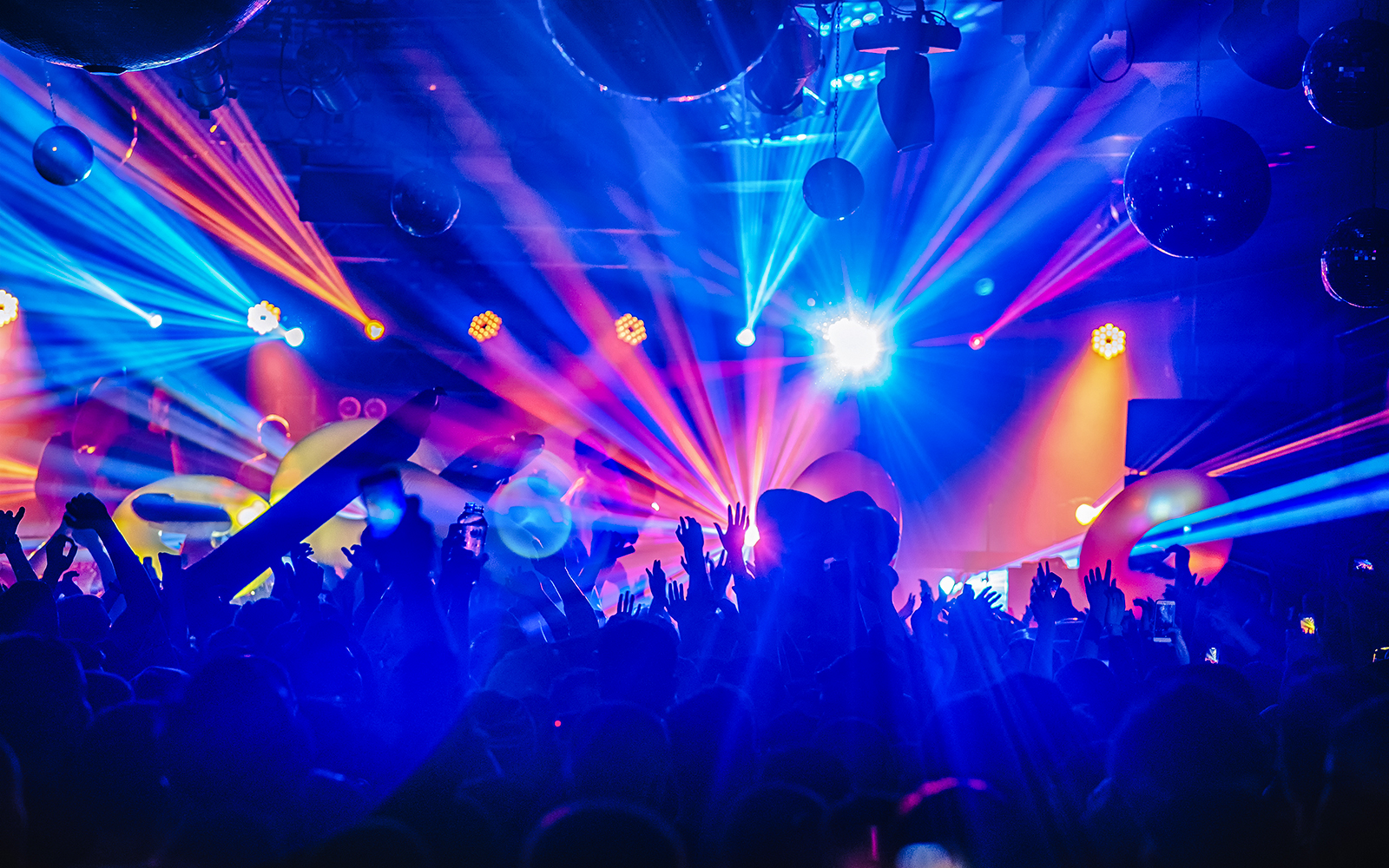 Crowd enjoying a DJ night club party rave with vibrant lights and music in a festive atmosphere.