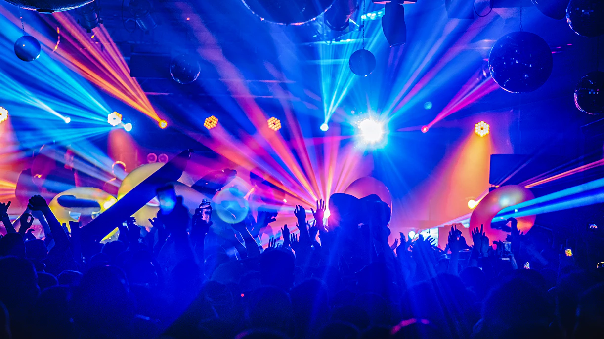Crowd enjoying a DJ night club party with colorful lights and music.