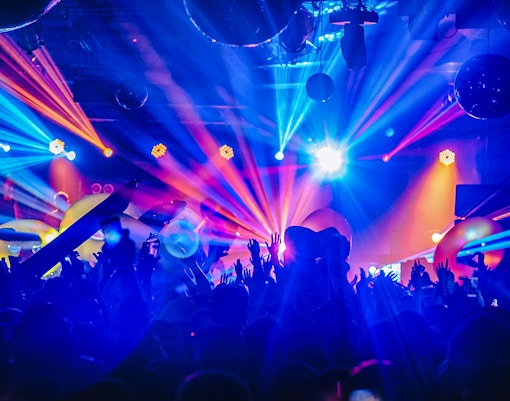 Crowd enjoying a DJ night club party rave with vibrant lights and music in a festive atmosphere.