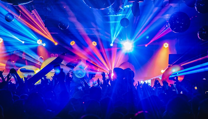 Crowd enjoying a DJ night club party rave with vibrant lights and music in a festive atmosphere.