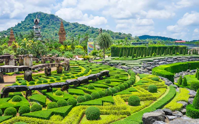 Nong Nooch Tropical Garden's manicured hedges and stone structures with mountain backdrop.