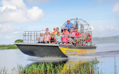 Guests on an airboat tour in the Everglades, gliding through wetlands.