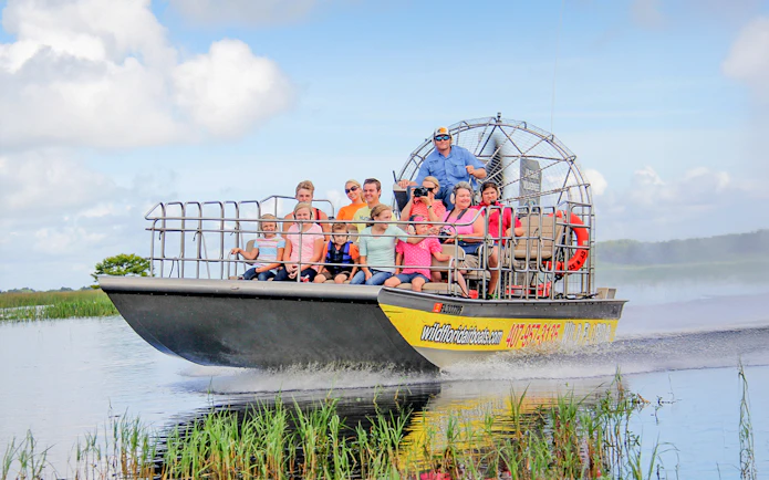 Guests on an airboat tour in the Everglades, gliding through wetlands.
