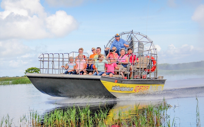 Guests on an airboat tour in the Everglades, gliding through wetlands.