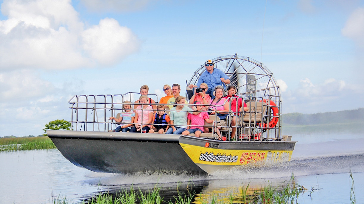 Guests on an airboat tour in the Everglades, gliding through wetlands.